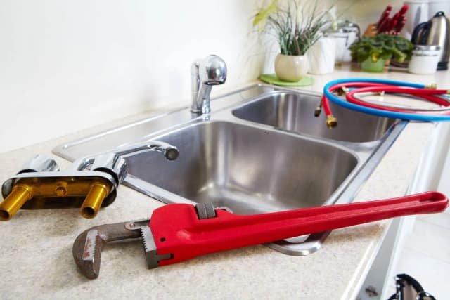 Llave Stillson colocada junto a un fregadero de cocina, lista para ser utilizada.