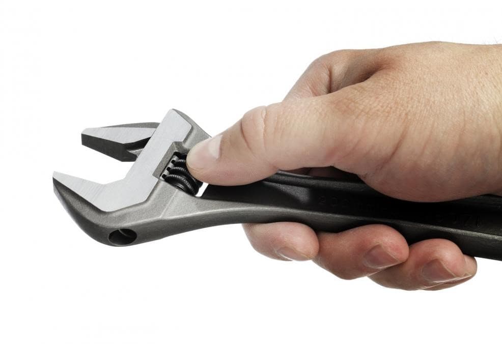 Mano sosteniendo una llave inglesa, herramienta esencial para trabajos de plomería.